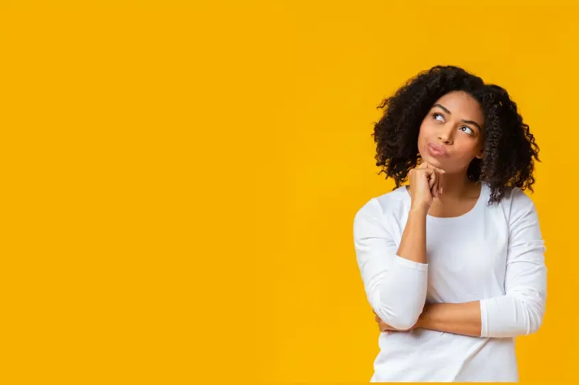 Mulher pensativa diante de um fundo amarelo